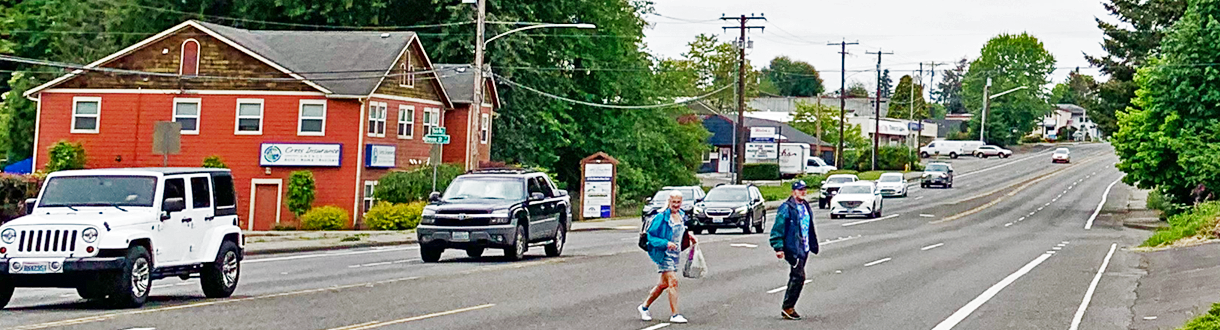 Image of 2 people crossing in the middle of a block on Martin Way.